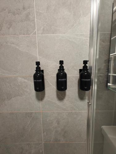 three bottles ofodorizers sit on the wall of a shower at Victoria's Bright Georgian Apartment in Liverpool