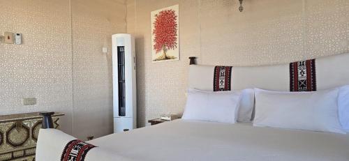 a bedroom with a large white bed with white pillows at Desert Escape Camp Wahiba in Ibrā