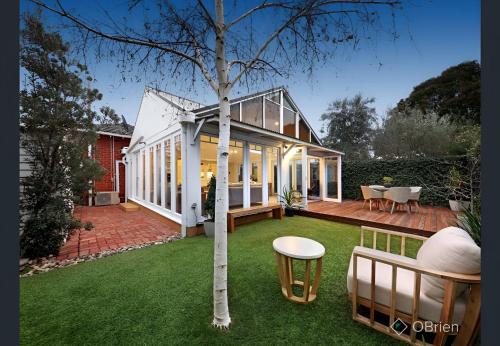 a house with a tree in the middle of a yard at Elegant Art Deco Gem Cosy 3BR Retreat in Carnegie