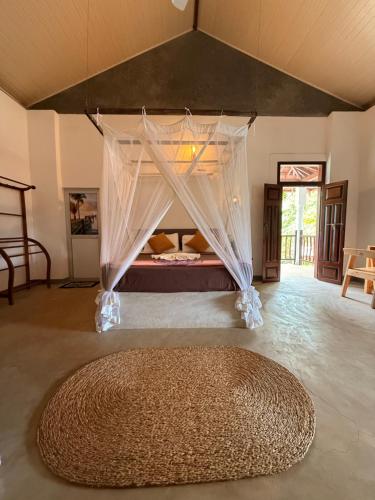 a bedroom with a bed with a canopy and a rug at Emma's Sea View in Hiriketiya