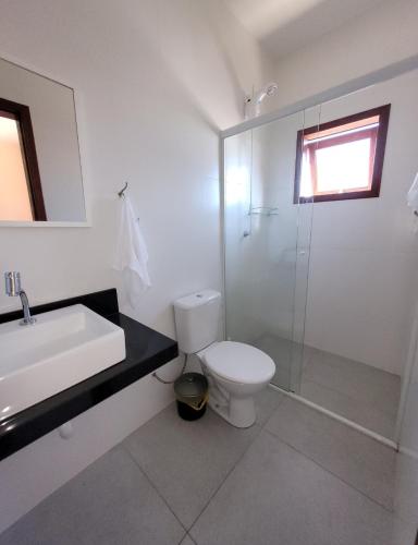 a bathroom with a toilet and a sink and a shower at Partiu Praia SC- Piscina, Ar condicionado, wi-fi, duas quadras da praia e centrinho in Pinheiro