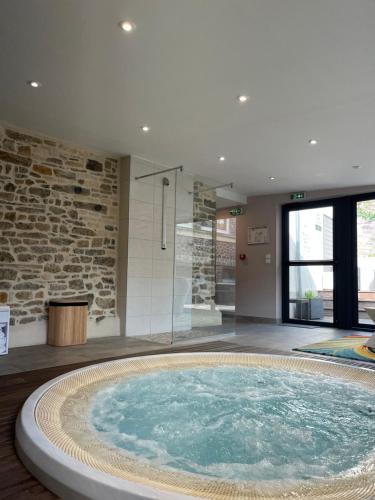 a large hot tub in a room with a stone wall at Logis Hotel Spa Restaurant Au Site Normand in Clécy
