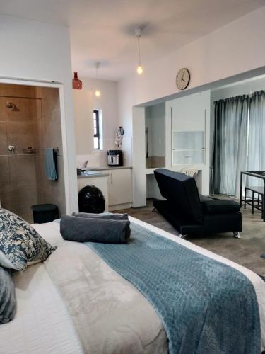 a bedroom with a large bed and a black chair at Driftwoods in Gqeberha