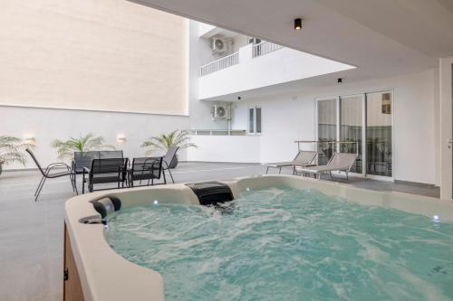 a jacuzzi tub in a living room with tables and chairs at HORIZON SUITES by the Sea in St Paul's Bay