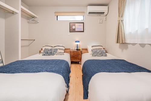 two twin beds in a room with a window at Mi-Villa SHIBUYA HONMACHI in Tokyo