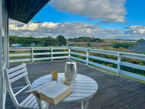 a table with a book and a vase on a deck at Sommerhus Med Havudsigt Ved Faldsled in Faldsled