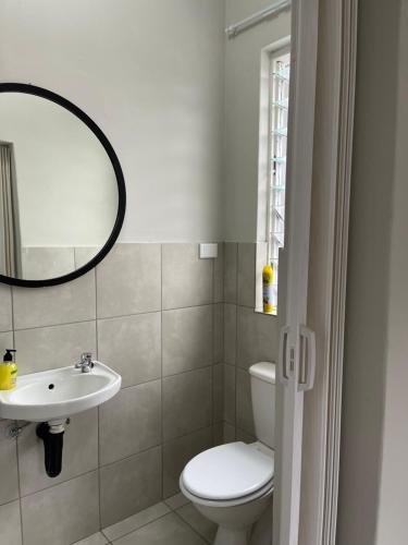 a bathroom with a toilet and a sink and a mirror at Lani Accommodation in Pretoria