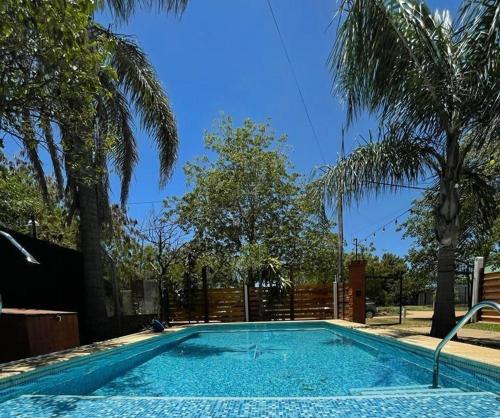 a swimming pool in a yard with palm trees at Casa con Pileta a Cuadras de la Playa in Paso de la Patria