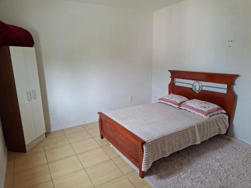 a bedroom with a wooden bed with pink pillows at Casa Ribeiro in Canguçu