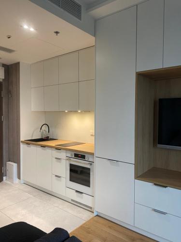 a kitchen with white cabinets and a flat screen tv at Chillout Luxury Touch Apartment - Free Parking Wola Tower in Warsaw