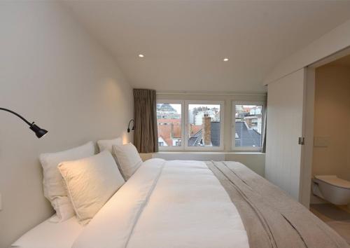 een groot wit bed in een kamer met een raam bij Studio Ocean by BLOSS, luxe studio in Knokke in Knokke-Heist