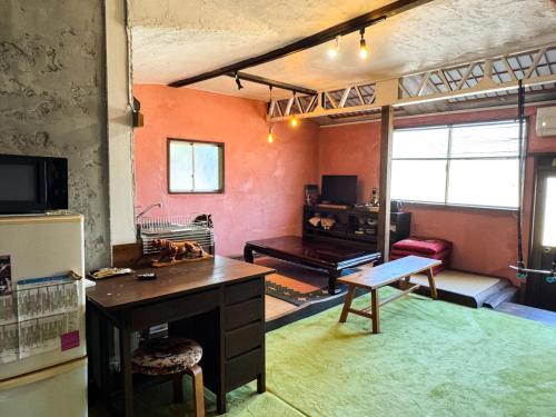 a living room with orange walls and a desk and a room at ギャラリー宿　INNAHOUSE ANDAGALLERY in Murotsu
