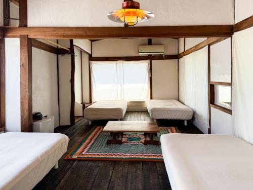 a room with three beds and a table in it at ギャラリー宿　INNAHOUSE ANDAGALLERY in Murotsu
