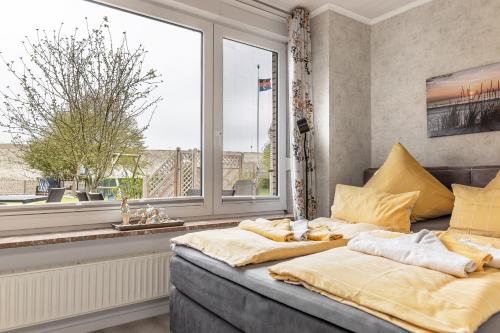 カロリーネンジールにあるFerienwohnung KUMM RIN - Oase an der Nordseeの大きな窓のある部屋のベッド