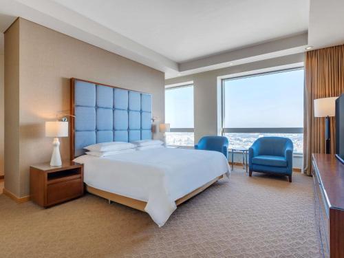 a bedroom with a large bed and two blue chairs at Swissôtel Al Ghurair Dubai - Deira & Creek in Dubai