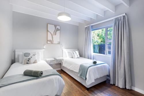a white bedroom with two beds and a window at Chive Cottage in Cape St Francis