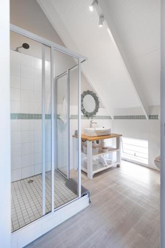 a white bathroom with a shower and a sink at Chive Cottage in Cape St Francis