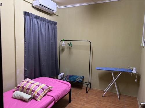 a room with a pink bed and a table at Kuzha Homestay in Kota Kinabalu