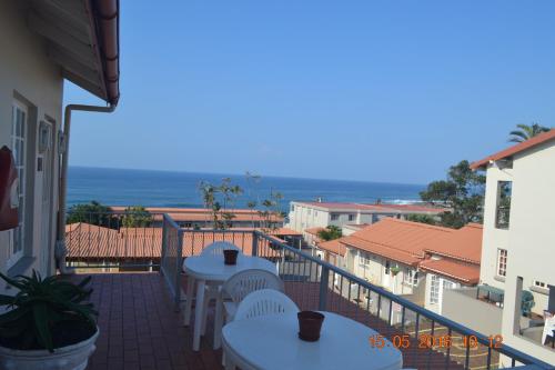 a balcony with tables and chairs and the ocean at Driftsands Sea View Flats in Uvongo Beach