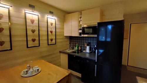 eine Küche mit einem schwarzen Kühlschrank und einem Holztisch in der Unterkunft Gentianes 6 in La Norma