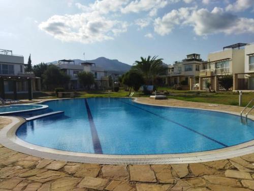 ein großer blauer Pool mit Gebäuden im Hintergrund in der Unterkunft Turtle Bay Village - Garden House in Kyrenia