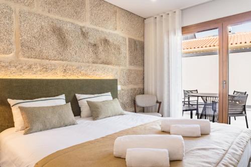 ein Schlafzimmer mit einem großen weißen Bett und einer Steinmauer in der Unterkunft LR Vintage 65 in Vila Real