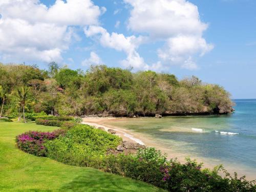 Blick auf einen Strand mit Bäumen und das Meer in der Unterkunft Raffles Bali in Jimbaran