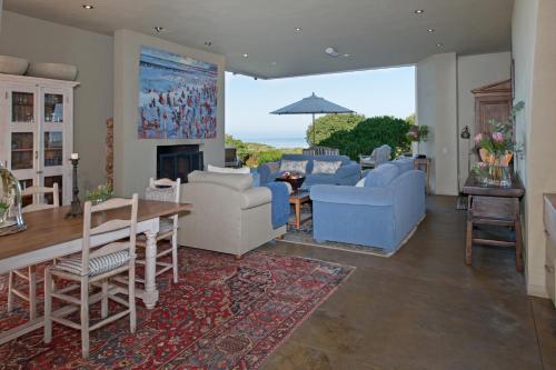 a living room with couches and a table and a fireplace at Mosselberg on Grotto Beach in Hermanus