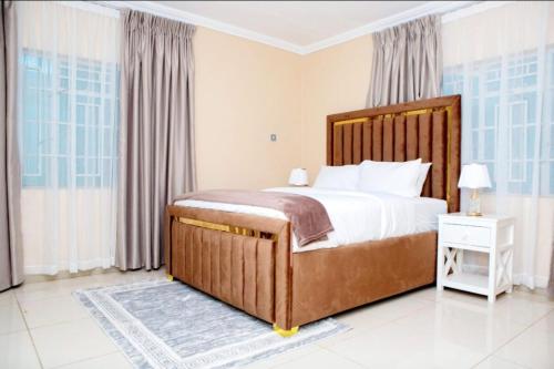 ein Schlafzimmer mit einem großen Bett mit einem hölzernen Kopfteil in der Unterkunft Sunrise Serenity Lux Homes in Lilongwe