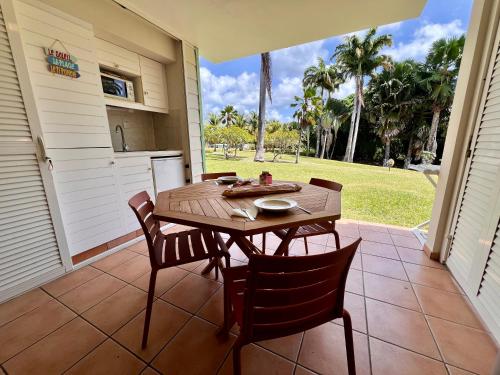 un patio con una mesa de madera y sillas en un porche en cœur d hibiscus P&V, en Sainte-Luce