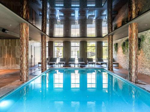 a large swimming pool with chairs in a building at Mercure Han-sur-Lesse in Han-sur-Lesse