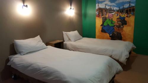 2 camas en una habitación con un cuadro en la pared en The Backpack Shack, en Mossel Bay
