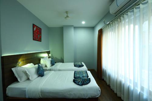 Un dormitorio con dos camas y una ventana. en DEWALING by Laughing Lama Hotels, en Phuntsholing