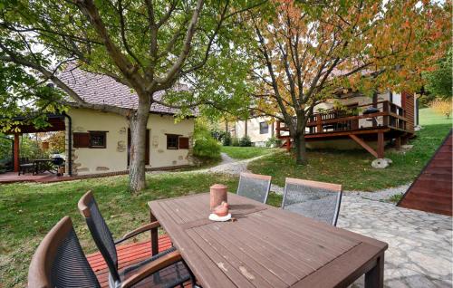 a wooden table in a yard with chairs and a house at Luka 10 in Kalnik