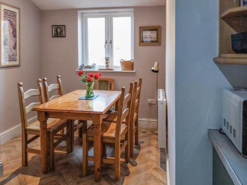 ein Esstisch mit Stühlen und einer Vase mit Blumen in der Unterkunft Flither Cottage in Staithes
