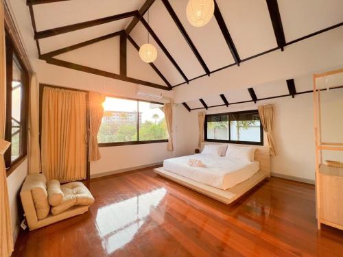 a bedroom with a large bed and two windows at Saga Pool House 5BR, 200m from BEACH in Pattaya North
