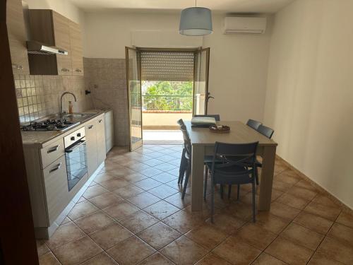 Una cocina con mesa y sillas y una cocina con ventana. en Casa vacanza Vega, en Roccalumera