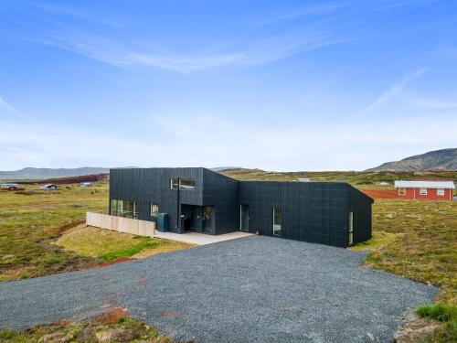 a black house in the middle of a field at Luxury Log Home with a Hot Tub in Selfoss