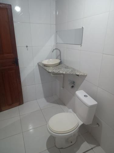 a white bathroom with a toilet and a sink at Suites para casais com area nativa in Manacapuru