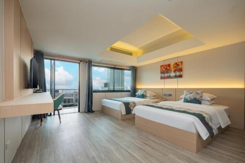 a hotel room with two beds and a desk at Xinmylin Boutique Resort Hotel in North Pattaya