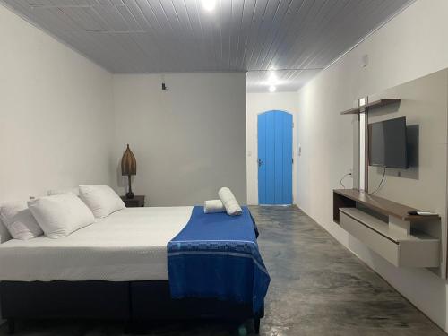 1 dormitorio con 1 cama con puerta azul y TV en San Sebastian Taipu de Fora, en Maraú