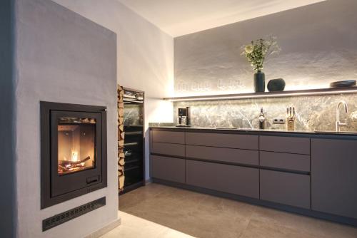 a living room with a fireplace in a kitchen at Stilvolles Ferienhaus Südsteiermark ruhige Lage top Aussicht & E-Ladestation in Eibiswald