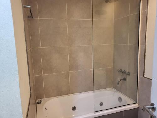 a bath tub with a shower with a glass door at Suite Rincon del Sol in Pinamar