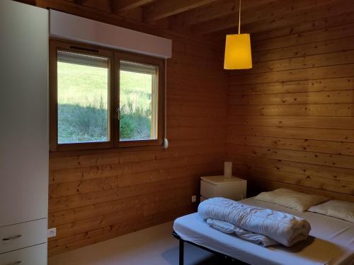 ein Zimmer mit einem Bett in einem Holzzimmer mit einem Fenster in der Unterkunft Grand Valtin : chalet écolo 4 étoiles 14 personnes in Ban-sur-Meurthe-Clefcy