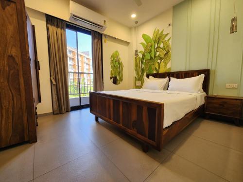 a bedroom with a bed and a large window at Bright Candolim 1BHK with Pool, Gym, Parking - 5 Minutes to Beach in Candolim