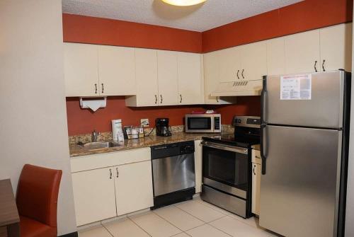 a kitchen with white cabinets and a stainless steel refrigerator at Hawthorn Suites in Erie