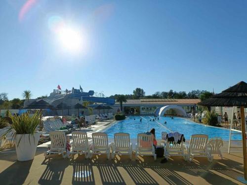 a swimming pool with chairs and people in the water at Mobil Home 45 m2 très luxueux 3 ch et 2 sdb - Camping 4 étoiles Les Charmettes 499 PROCHE FUN ZONE- Les Mathes in Les Mathes