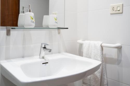 un bagno bianco con lavandino e specchio di Ático con vistas a Port Saplaya