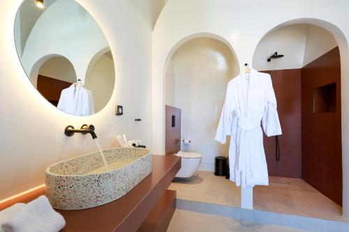 un bagno con un grande lavandino in pietra e uno specchio di Luna Santorini Suites a Pyrgos