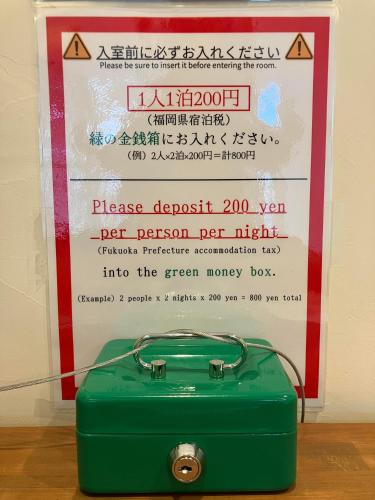 a green suitcase sitting in front of a sign at 2times Dormitory Hotel in Itoshima